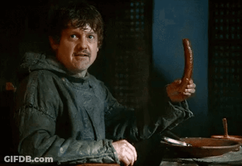 A Man In A Hooded Jacket Is Holding A Sausage In His Hand GIF