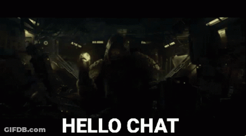 A Man In A Hooded Jacket Is Holding A Torch And Says Hello Chat In The Background GIF