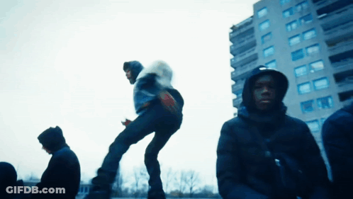 A Man In A Hooded Jacket Is Jumping In The Air GIF