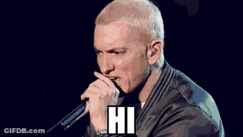 A Man In A Hooded Jacket Is Singing Into A Microphone With The Words " My Name Is " Below Him GIF