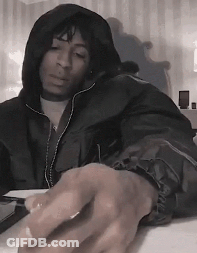 A Man In A Hooded Jacket Is Sitting At A Table With His Hands On The Keyboard . GIF