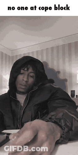A Man In A Hooded Jacket Is Sitting At A Table With The Words No One At Cope Block Above Him GIF