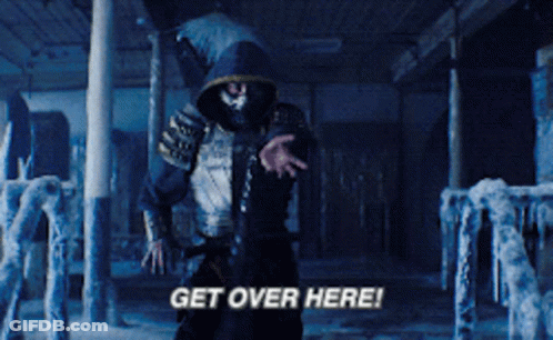 A Man In A Hooded Jacket Is Standing In A Dark Room And Says Get Over Here GIF