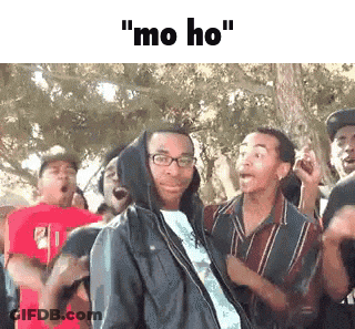 A Man In A Hooded Jacket Is Standing In Front Of A Crowd Of People And Says `` Mo Ho '' . GIF