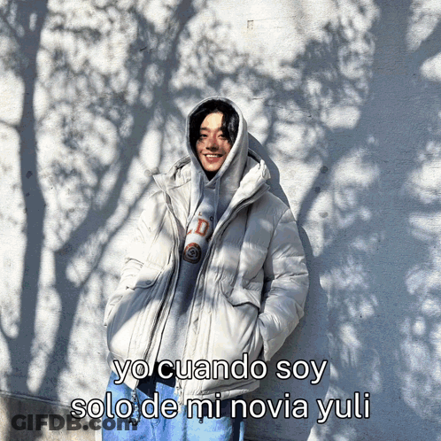 A Man In A Hooded Jacket Is Standing In Front Of A Wall With A Caption That Says Yo Cuando Soy GIF