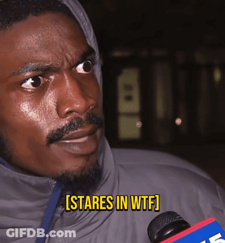 A Man In A Hooded Jacket Says [ Stares In Wtf ] While Holding A Microphone GIF