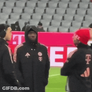A Man In A Hooded Jacket With The Letter T On The Back GIF