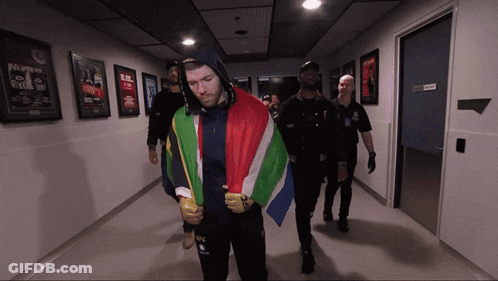 A Man In A Hooded Jacket With The Word Ufc On It Is Walking Down A Hallway GIF