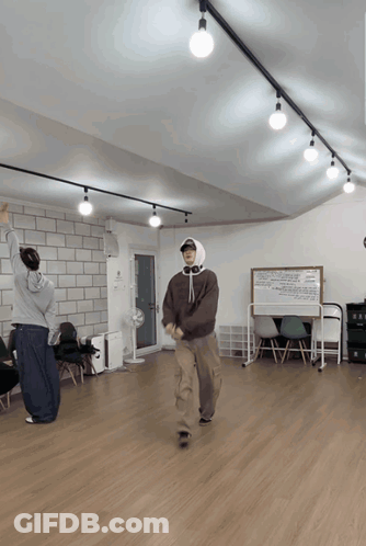 A Man In A Hooded Sweatshirt Is Dancing In A Room GIF