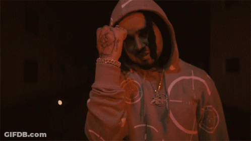 A Man In A Hoodie Is Giving The Middle Finger In Front Of A Fire GIF