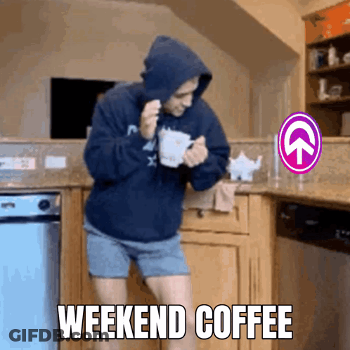 A Man In A Hoodie Is Holding A Cup Of Coffee In A Kitchen With The Words Weekend Coffee Above Him GIF