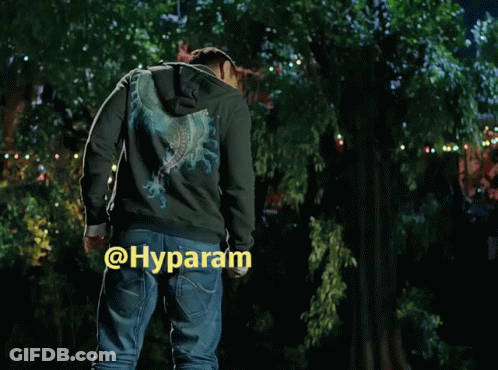 A Man In A Hoodie Is Standing In Front Of A Tree With The Word Hyparam On The Bottom Right Corner GIF