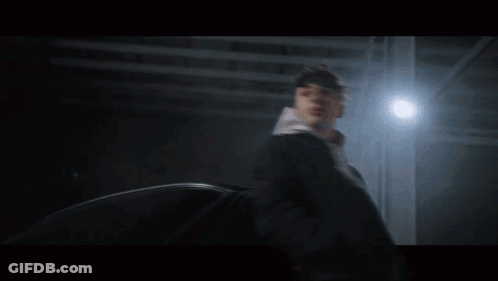 A Man In A Hoodie Is Standing Next To A Car At Night GIF