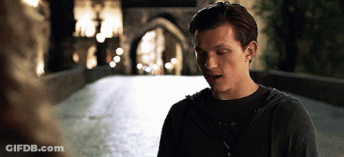 A Man In A Hoodie Is Standing On A Bridge At Night GIF