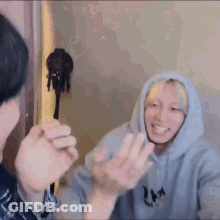 A Man In A Hoodie Is Talking To Another Man In A Room While Another Man Looks On . GIF