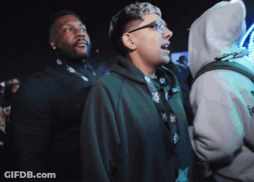 A Man In A Hoodie With The Word Icon On It Stands In A Crowd GIF