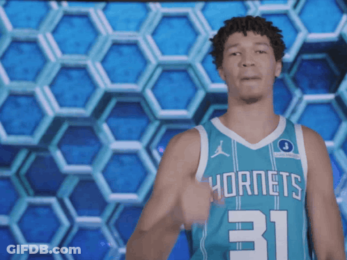 A Man In A Hornets Jersey Stands In Front Of A Honeycomb Pattern GIF