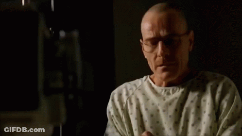 A Man In A Hospital Gown Is Crying While Sitting On A Bed . GIF