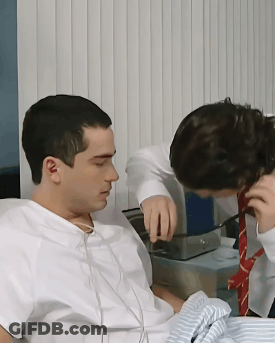 A Man In A Hospital Gown Is Talking To Another Man In A Red Tie GIF
