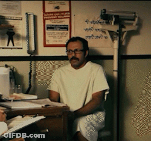 Man In Hospital Gown Sitting At Desk With Malaria Poster GIF