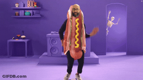 A Man In A Hot Dog Costume Is Dancing In A Purple Room GIF