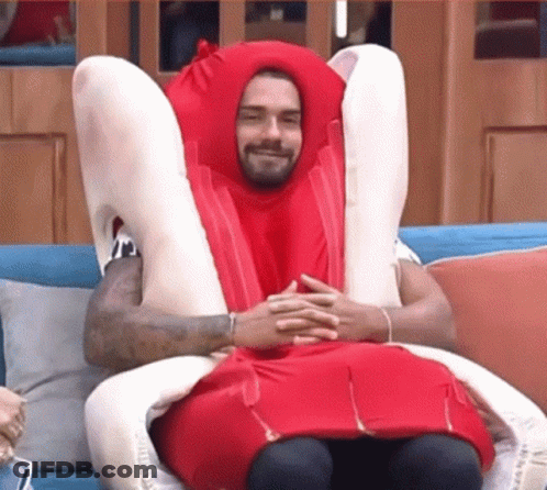 A Man In A Hot Dog Costume Is Sitting On A Couch With His Legs Crossed . GIF