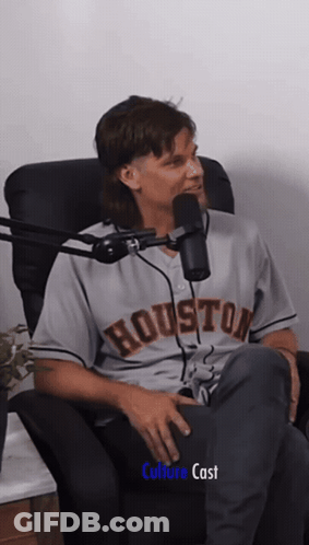 A Man In A Houston Jersey Sits In A Chair In Front Of A Microphone GIF