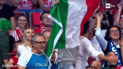 A Man In A Italia Shirt Is Holding A Flag In A Crowd GIF