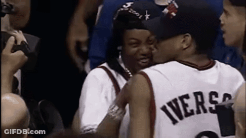 A Man In A Iverson Jersey Is Kissing Another Man In A Crowd . GIF