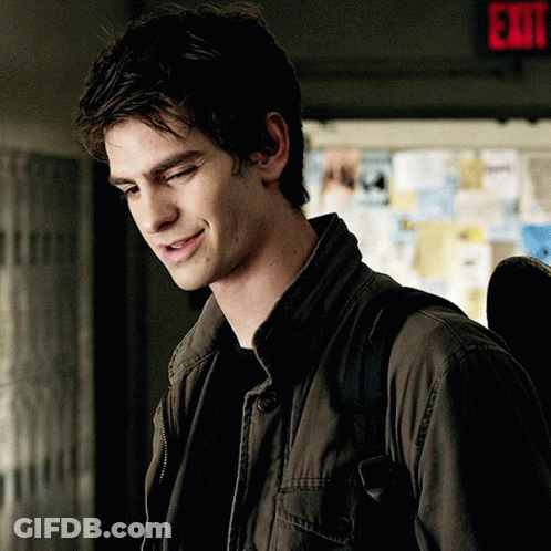 A Man In A Jacket Is Smiling In Front Of An Exit Sign GIF