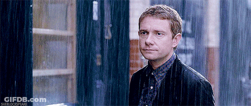 A Man In A Jacket Is Standing In The Rain Looking At The Camera . GIF