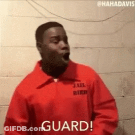 A Man In A Jail Uniform Is Standing In Front Of A Brick Wall With His Mouth Open . GIF