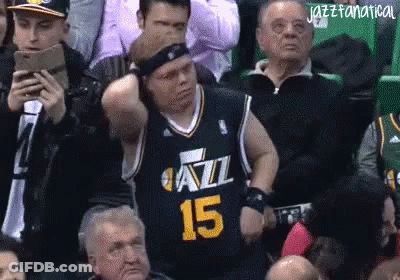 A Man In A Jazz Jersey Is Sitting In The Stands Watching A Game GIF