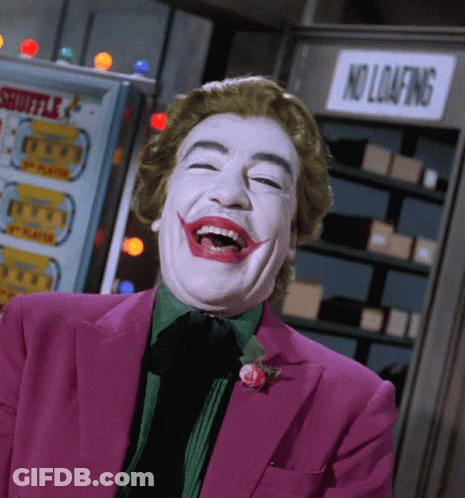 A Man In A Joker Costume Is Laughing In Front Of A No Loafing Sign GIF