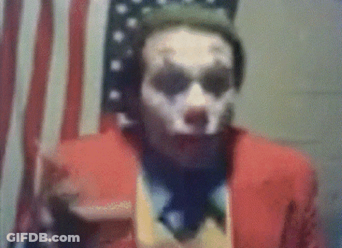 A Man In A Joker Costume Is Standing In Front Of An American Flag . GIF