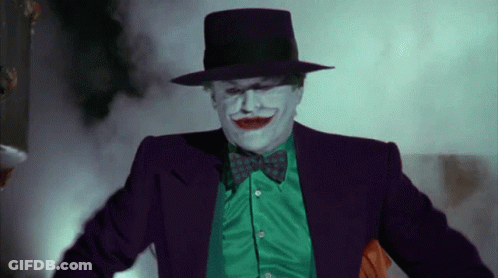 A Man In A Joker Costume Is Wearing A Green Shirt And A Purple Hat GIF