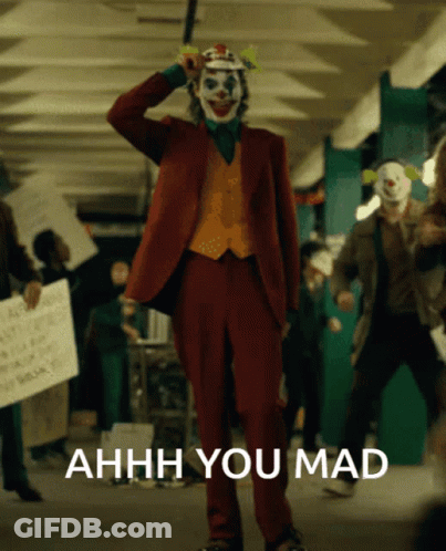 A Man In A Joker Costume Stands In Front Of A Sign That Says Ahhhh You Mad GIF
