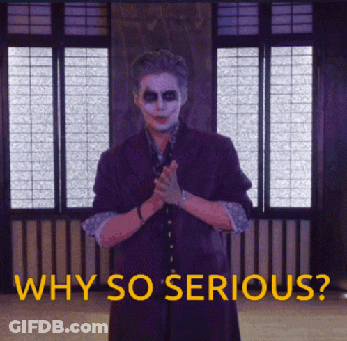 A Man In A Joker Costume Stands In Front Of A Window With The Words Why So Serious Below Him GIF