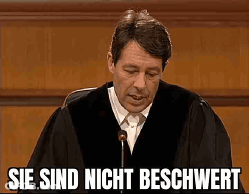 A Man In A Judge 'S Robe Is Giving A Speech In Front Of A Microphone In A Courtroom . GIF