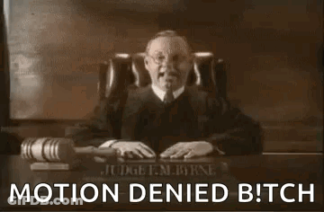 A Man In A Judge 'S Robe Is Sitting At A Desk With A Microphone And A Hammer . GIF