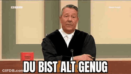 A Man In A Judge 'S Robe Is Sitting At A Table In Front Of A Microphone And Says Du Bist Alt Genug GIF