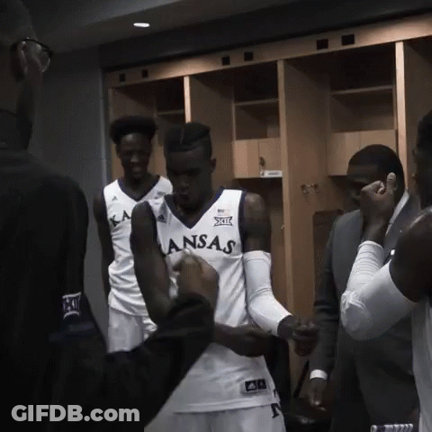 A Man In A Kansas Jersey Is Being Helped By Another Man GIF