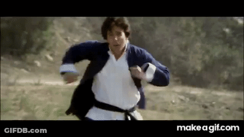 A Man In A Karate Outfit Is Running Through A Field . GIF
