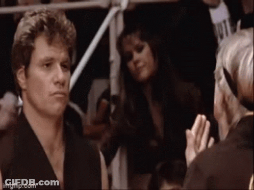 A Man In A Karate Uniform Is Standing In A Crowd Of People . GIF