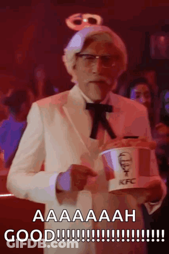 A Man In A Kfc Costume Is Holding A Bucket Of Fried Chicken GIF
