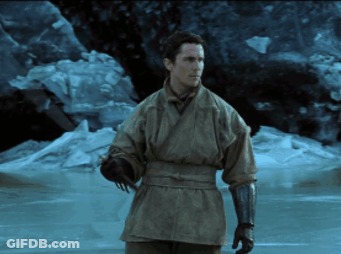 A Man In A Kimono And Gloves Stands In Front Of A Frozen Body Of Water GIF