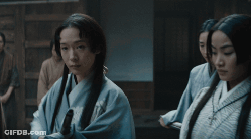 A Man In A Kimono Holds Out His Hand Towards A Group Of Men GIF