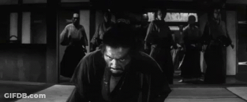 A Man In A Kimono Is Kneeling Down In Front Of A Group Of Samurai . GIF