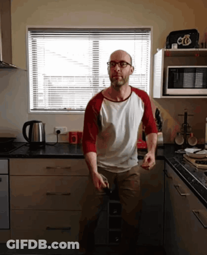 A Man In A Kitchen Wearing Glasses And A Red And White Shirt With The Letter O On It GIF