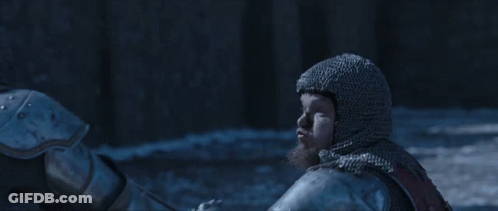 A Man In A Knight 'S Armor Is Holding A Sword In Front Of A Crowd With A Banner That Says Mm GIF